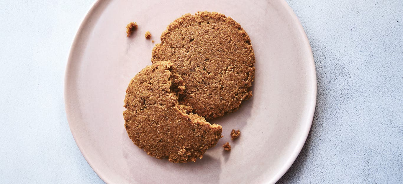 Molasses Spice Cookies on a plate, with a large bite out of one cookies