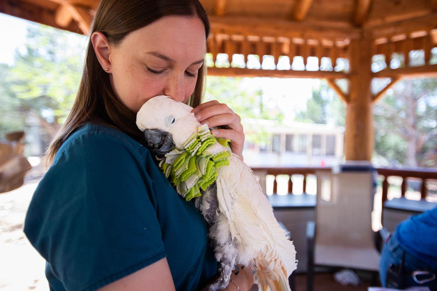 A woman snuggles with a rescued bird at Best Friends Animal Sanctuary