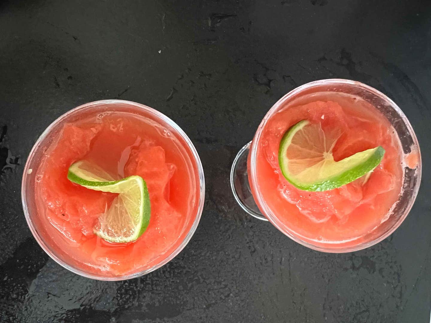 two glasses of watermelon margarita mocktail shown from above garnished with lime slices